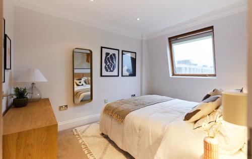 um quarto branco com uma cama e uma janela em The London Cradle - Spacious 1BDR Flat em Londres