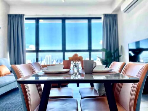 a dining room with a table and chairs and a large window at Urban Suites George Town in Jelutong