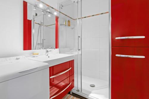 een badkamer met rode kasten en een glazen douche bij Boulouris in Saint-Raphaël