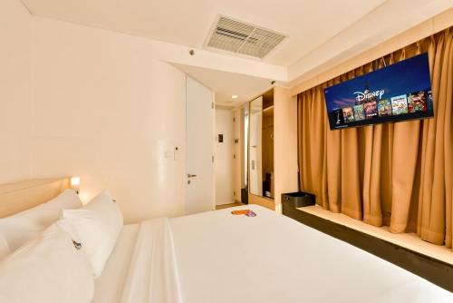 a bedroom with a white bed with a tv on the wall at Maxone Premier Melawai in Jakarta