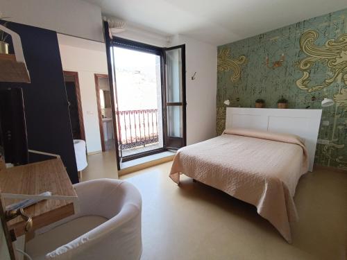 1 dormitorio con 1 cama, 1 silla y 1 ventana en Hotel Rural Martin, en Baños de Montemayor
