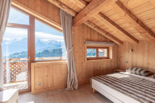 une chambre avec un lit et une grande fenêtre dans l'établissement Chalet Mont Blanc - Conciergerie de la Yaute, à Cordon