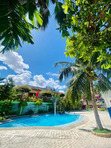 a swimming pool with a palm tree in the foreground at JSJS Mountain Resort powered by Cocotel in Talaga