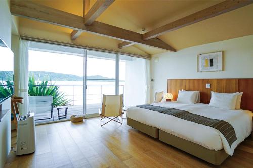 a bedroom with a large bed and a large window at Miru Amami in Tatsugo