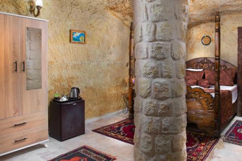Romantic Cave Hotel في نوشهر: غرفة نوم بسرير وجدار حجري