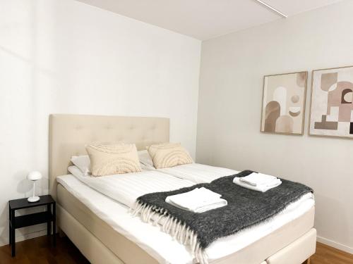 a white bedroom with a bed with a black blanket at Aurora City Studio By BookLapland in Rovaniemi