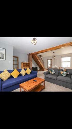 a living room with a blue couch and a wooden table at Whole house in Wiltshire in Chippenham