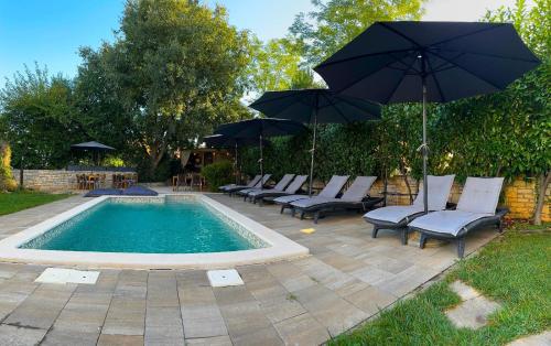 a group of chairs and umbrellas next to a pool at Rooms and Apartments IstraSoley in Bale