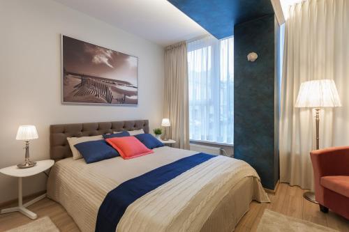 Raugyklos apartamentai في فيلنيوس: غرفة نوم بسرير كبير ومخدات زرقاء وحمراء