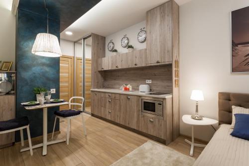 una cocina con armarios de madera, mesa y sillas en Raugyklos apartamentai, en Vilna