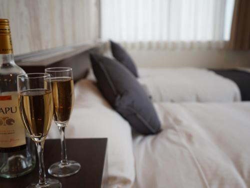 two glasses of champagne on a table next to a bed at Hotel New Gaea Domemae in Fukuoka