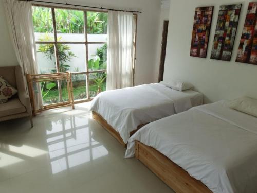 sypialnia z 2 łóżkami i dużym oknem w obiekcie Deepblue vila w mieście Pulukan