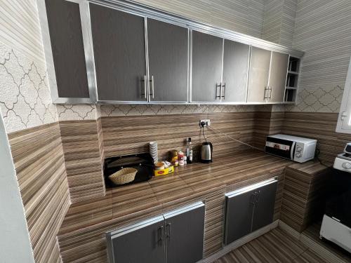 a kitchen with wooden cabinets and a counter top at Viva Hostel Group Muscat in Muscat