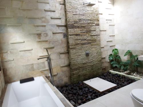 y baño con pared de piedra y ducha. en Deepblue vila en Pulukan