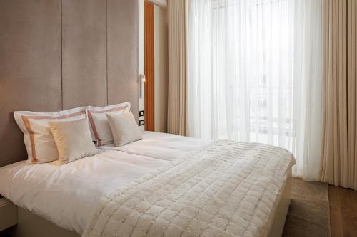 a bedroom with a large white bed with a window at Skylark Central Aparthotel in Braşov
