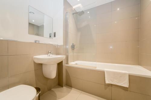 倫敦的住宿－StayInn Greenwich，浴室配有盥洗盆、卫生间和浴缸。