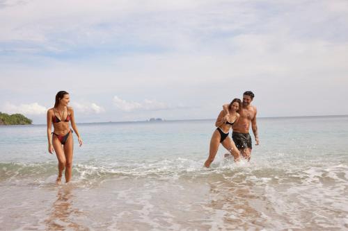 a group of people walking in the water on the beach at W Costa Rica Resort – Playa Conchal in Playa Conchal