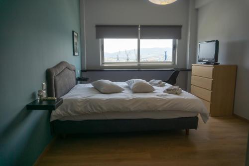 una camera da letto con un letto, una TV e una finestra di Limani Volos Apartment a Volos