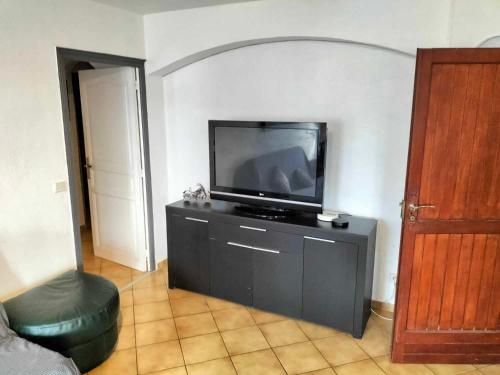 uma sala de estar com uma televisão de ecrã plano num centro de entretenimento em Appartement dans villa Niçoise em Nice