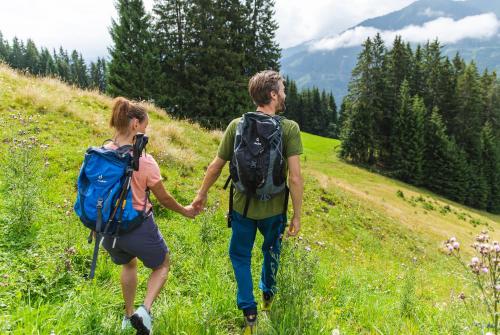 a man and a woman walking down a hill holding hands at JUFA Alpenhotel Saalbach-Jokercard im Sommer inklusive in Saalbach Hinterglemm