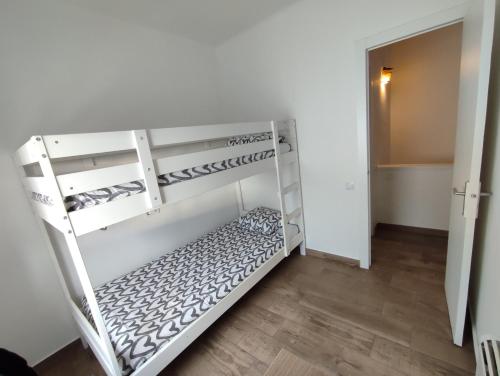 um quarto com beliches brancos e piso em madeira em Estancia Rural Tranquila em Lliçà d'Amunt