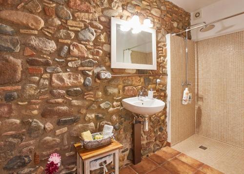 een stenen badkamer met een wastafel en een spiegel bij Rincón de piedra BCN in Corró de Vall
