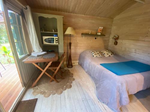 Dormitorio con cama y escritorio en una cabaña en Le chalet du Jardin caché, en Marmande