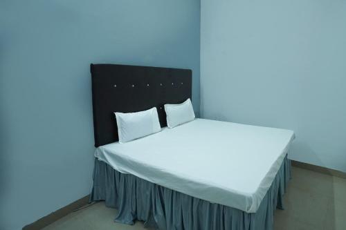 een bed met witte lakens en kussens in een kamer bij OYO Hotel Shining Star in Bhilai