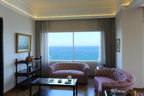 a living room with two couches and a large window at Warwick Palm Beach Hotel in Beirut