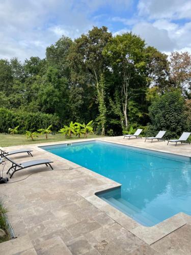 una piscina con due sedie a sdraio accanto di Maison Périgoudine a Saint-Philippe-dʼAiguille
