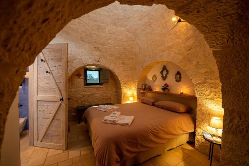 um quarto com uma cama numa parede de pedra em Le Dieci Porte em Alberobello