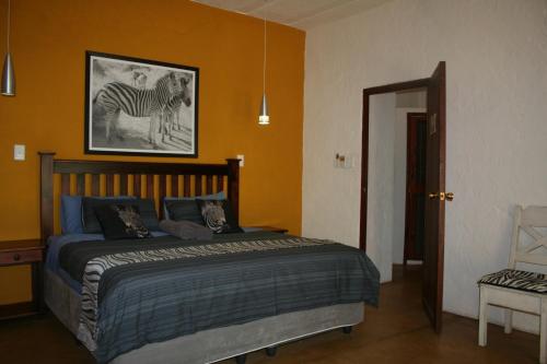 a bedroom with a bed with a picture of a zebra at Kiburi Lodge @ Kruger, a secluded Bushveld getaway in Marloth Park