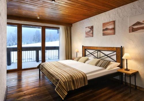 a bedroom with a large bed and a balcony at Chalets Jasná Collection Centrum in Demanovska Dolina