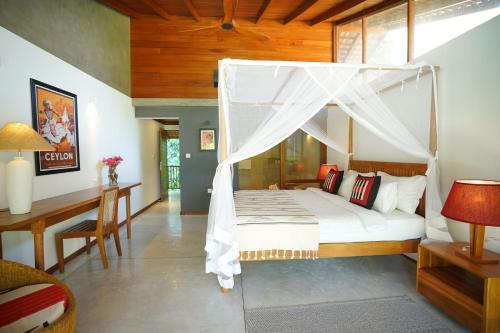 a bedroom with a bed with a canopy at Maison Samara in Hikkaduwa