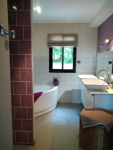 La grande salle de bains est pourvue d'une baignoire et de deux lavabos. dans l'établissement Villa avec piscine chauffée Périgord Dordogne, à Marnac