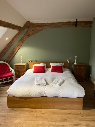 a bedroom with a large white bed with red pillows at LA CHARMILLE Jolie maison de campagne 14 personnes piscine calme in Entrains-sur-Nohain