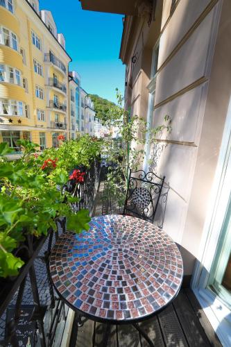 a patio with a table and chairs on a balcony at Boutique Hotel Ambiente ****+ in Karlovy Vary