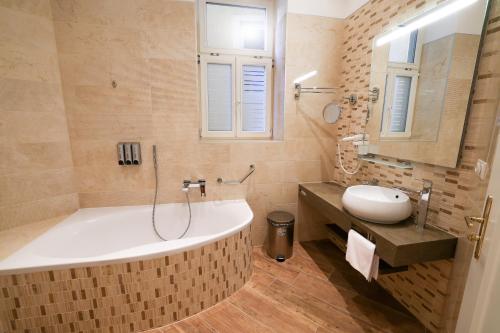 a bathroom with a large tub and a sink at Boutique Hotel Ambiente ****+ in Karlovy Vary