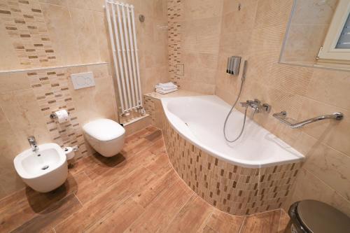 a bathroom with a tub and a toilet and a sink at Boutique Hotel Ambiente ****+ in Karlovy Vary