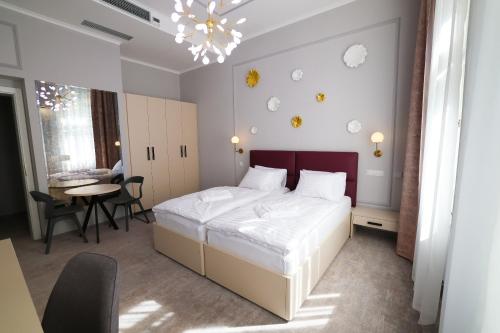a bedroom with a bed and a table and a chandelier at Boutique Hotel Ambiente ****+ in Karlovy Vary