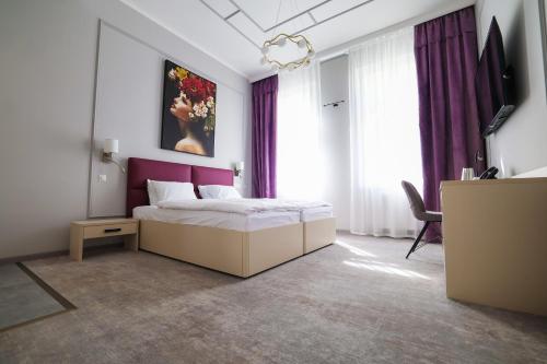a bedroom with a bed with a purple headboard at Boutique Hotel Ambiente ****+ in Karlovy Vary