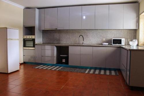 a kitchen with white cabinets and a white refrigerator at Casa da Tapada in Memorial