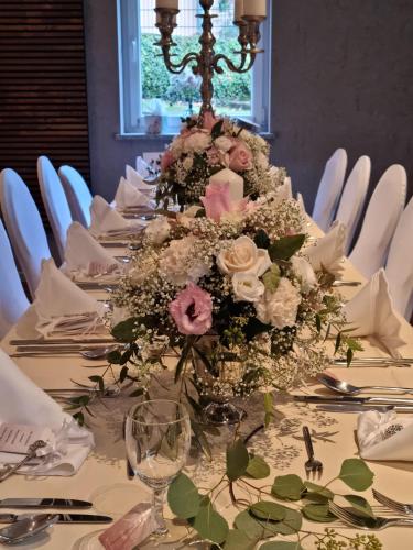 a table with a centerpiece of flowers on it at Hotel & Restaurant 4 Winden in Windhagen