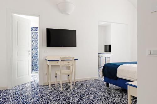 Hotel Da Raffaele في ايسكيا: غرفة نوم بسرير ومكتب وتلفزيون