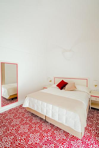 a bedroom with a large white bed and a mirror at Hotel Da Raffaele in Ischia