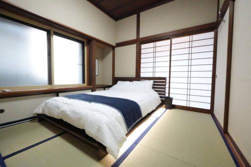 1 dormitorio con 1 cama en una habitación con ventanas en シアタールーム付き！駅徒歩7分の好立地！【藍Restvillage松本】, en Matsumoto