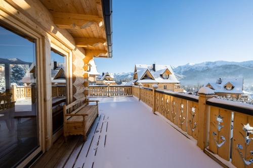 a balcony with a bench and snow covered mountains at udanypobyt Tatrzańskie Domy in Kościelisko