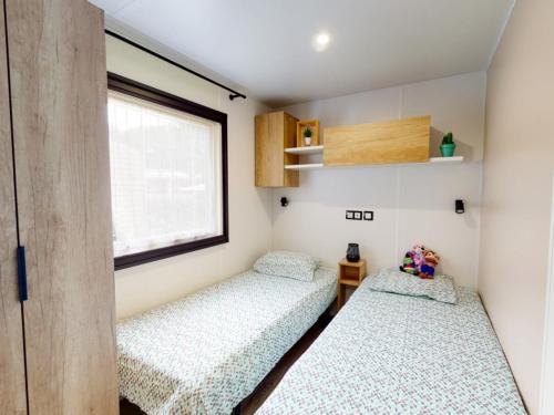 deux lits dans une petite pièce avec une fenêtre dans l'établissement Mobil-Home Eucalyptus 1, à Valras-Plage