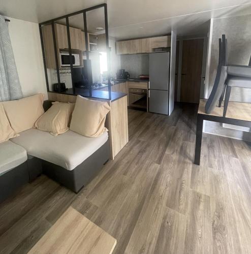 un salon avec un canapé et une cuisine dans l'établissement Mobil-Home Eucalyptus 1, à Valras-Plage