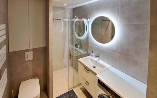 a bathroom with a sink and a shower with a mirror at Planty Park Apartament in Nowy Sącz